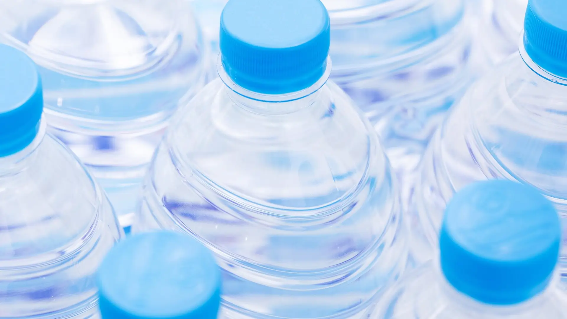 Vattenflaskor av plast med blå korkar